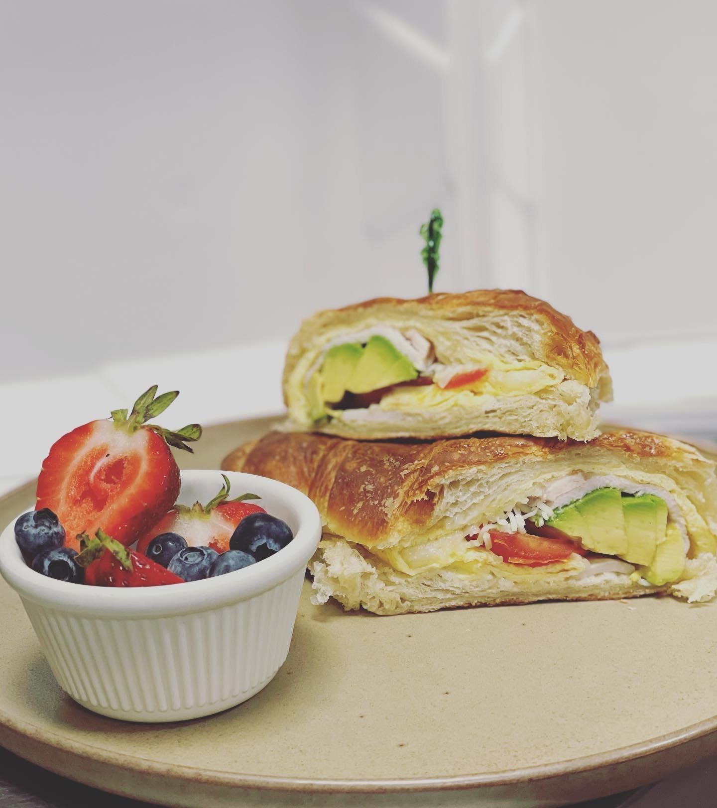 A croissant sandwich with avocado and fresh berries at Parisien Bakery
